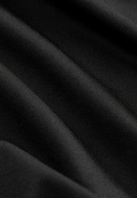 Tessuto nero con una texture liscia, che mostra delle leggere righe e pieghe, indicando flessibilità e un motivo di tessitura uniforme.