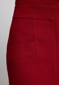 Rode broek met een textuurstof, hoge tailleband en een enkele zijzak met een platte vormgeving.