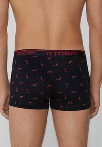 Námořnické trenýrky s potiskem červených chilli papriček, elastický pas s logem "TEZENIS", hladká textura a přiléhavý střih.