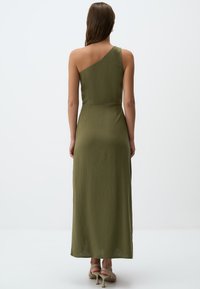 Olivgrünes, einseitiges Midikleid aus leichtem Stoff, mit einem taillierten Schnitt und einem fließenden Rock, kombiniert mit Riemchenheels.