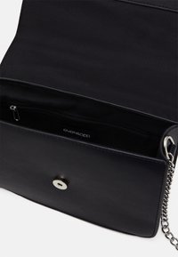 Černá taška z umělé kůže s hladkou texturou, vybavená přihrádkou na zip a stříbrným zapínáním na cvok. Doplněná o řetízkový popruh.