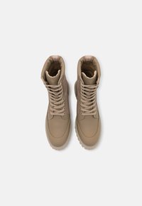 Beige High-Top-Boots mit glatter Außenseite, kontrastierenden Suedepanelen, runden Schnürsenkeln und einer strukturierten Gummisohle.
