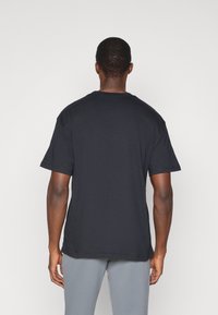 T-shirt en coton noir avec col rond et manches courtes, présentant un design uni et une coupe droite, montrant la vue arrière.