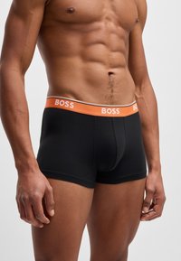 Boxer-briefs noirs avec une ceinture logo orange. Fabriqués en tissu doux, avec un design ajusté et une texture lisse pour le confort.