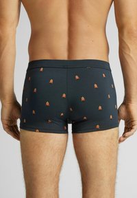 Czarne bokserki wykonane z elastycznej tkaniny, ozdobione powtarzającym się wzorem małych kolorowych postaci. Pas biodrowy dopasowany, bez widocznych elementów zapięcia.