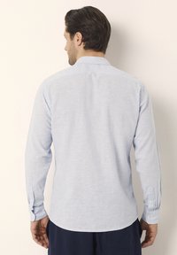 Lichtblauw longsleeve shirt gemaakt van gestructureerde stof, met een puntkraag, knopenmanchetten en een rechte zoom.