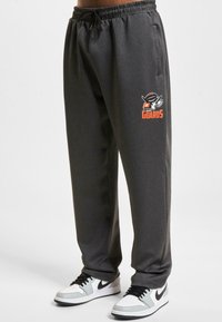 Grå sweatpants med elastisk talje, sidelommer og et kontrastfarvet orange og sort "Guards" logo på venstre ben.