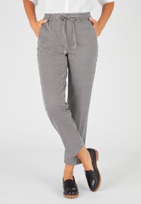 Schwarz-weiße, kariert gemusterte Hose mit einem elastischen Bund und Kordelzug, zwei Seitentaschen und schmal zulaufenden Beinen.