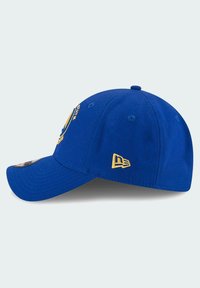 Gorra de béisbol azul con visera curva, que presenta detalles de logotipo bordados en amarillo y un acento de bandera New Era en el lateral. Material de algodón.