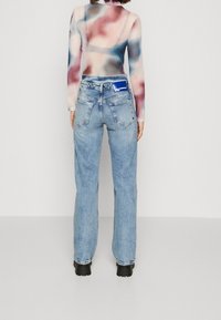 Ljusblå raka jeans med en blekt finish, med en bakfickdesign och en blå varumärkesetikett på midjebandet.