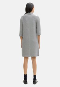 Robe à rayures avec une coupe droite, manches trois quarts, fabriquée en tissu léger, présentant des rayures horizontales noires et blanches alternatives.