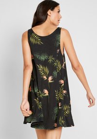 Vestito nero senza maniche con stampa tropicale caratterizzata da foglie verdi e fiori rosa; realizzato in tessuto morbido, con una vestibilità comoda e un orlo curvato.