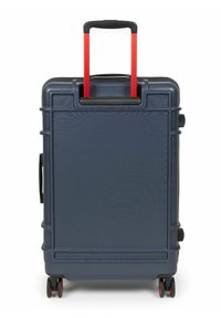 Navy hard-shell suitcase with textured surface, red telescopic handle, and four swivel wheels for easy mobility. Two side handles included.