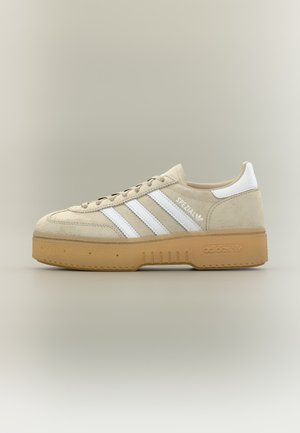 Baskets Adidas beige avec des bandes blanches et une languette au talon, semelle en gomme, texte "SPEZIAL" sur le côté, vues de l'extérieur sur fond neutre.