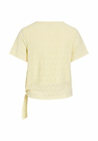 Haut en maille jaune clair à manches courtes avec motif ajouré en forme de losange et détail de nœud sur le côté à l'ourlet.