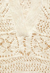 Pull en tricot crème, avec un décolleté en V, des motifs en dentelle complexes et une texture travaillée. Tissu doux et léger.