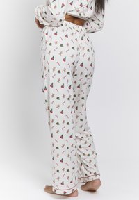 White pajama pants with a repeating pattern of gingerbread men, Christmas trees, and candy canes; features an elastic waistband and red accents.