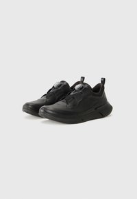 Black athletic shoes featuring a sleek design, rounded shape, textured surface, and two gray knobs for adjustment. Rubber outsole and pull tabs.
