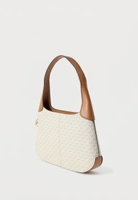 Mała beżowo-brązowa torebka z powtarzającym się wzorem logo „MK” i szerokim skórzanym paskiem, stojąca na jednolitym jasnym tle.