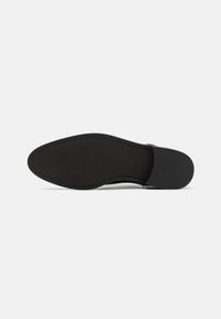Semelle de chaussure en cuir noir avec une surface lisse, un bout rond et un bord cousu. Présente des crampons en caoutchouc pour une meilleure adhérence et durabilité.