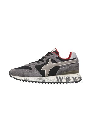 Low-top sneaker with black, grey suede, beige star design, red collar lining, patterned white sole with black text and rugged black outsole.