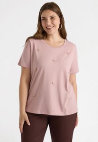 Camiseta rosa de manga corta hecha de algodón suave, con embellishments florales en la parte delantera. Cuello redondo y corte relajado.