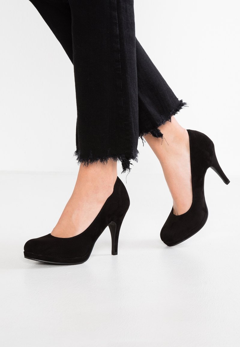 Escarpins en daim noir à bout rond et plateforme, avec un talon aiguille fin et haut. Portés avec un jean noir cropped effiloché.