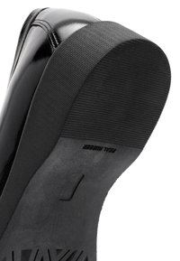 Zwarte sneaker zool met gestructureerd rubber en gevormde grippatronen. Glanzend bovenmateriaal met accentstiksel details aan de rand.