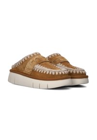 Des chaussures en suédine brune à enfiler, avec un accent tissé texturé le long du bord supérieur et une semelle épaisse en caoutchouc blanc.