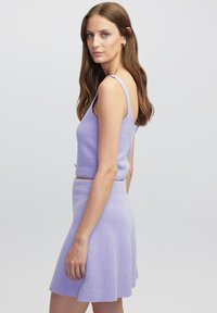 Lila tweedelige set bestaande uit een strak cropped tanktop met smalle bandjes en een uitlopende mini-jurk gemaakt van textured stof.