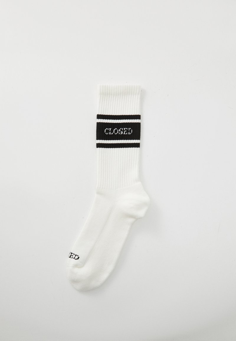 Chaussette en coton blanc avec texture côtelée, arborant une bande noire avec le texte "CLOSED" et deux rayures noires. Design de longueur classique.