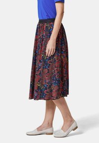 Une jupe à mi-mollet avec taille élastique, de couleur bleu marine, ornée de rayures horizontales colorées dans des motifs rouges, jaunes et verts.