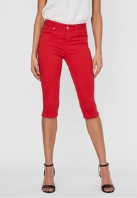 Röda capribyxor i bomullsblandning med figurnära passform, fem fickor och rak skärning som slutar precis under knäet.