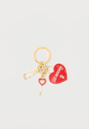 Gold keyring with red heart-shaped lock reading "LOVE MOSCHINO" and matching key charm on white background.