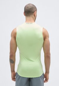 Light green sleeveless athletic shirt made of stretchy material, featuring a smooth texture and a curved hemline with "NIKE PRO" logo at the neck.