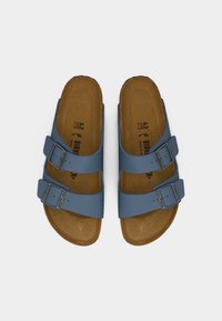Μπλε σανδάλια Birkenstock με δύο ρυθμιζόμενες λουρίδες με αγκράφες και ποδία από φελλό, σε θέαση από πάνω σε λευκό φόντο.