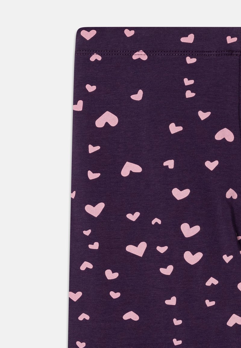 Fioletowe legginsy z wzorem małych różowych serc rozsianych po całej powierzchni. Wykonane z miękkiego materiału o gładkiej fakturze.