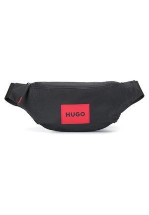 Musta kangasvyölaukku, jossa punainen suorakaiteen muotoinen merkki, jossa lukee "HUGO", sekä vetoketjullinen yläaukko.