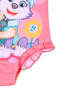 Maillot de bain rose avec des bords volants, arborant un chien cartoon à l'avant et des motifs floraux, fabriqué en tissu extensible et lisse.