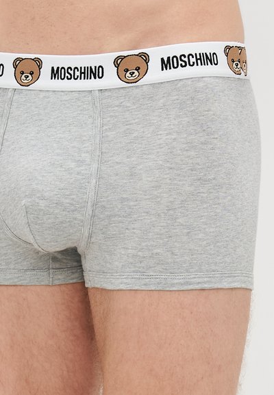 Boxers cinzentos com uma textura suave, apresentando uma cinta branca adornada com gráficos de ursos castanhos e o texto "MOSCHINO".