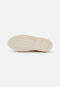 Sole světle béžového tenisky Converse All Star s diamantovým a čárovým vzorem na bílém pozadí.
