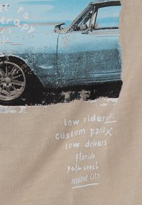 Coche vintage azul con ruedas negras y texto manuscrito sobre low riders, piezas personalizadas, Florida, Palm Beach y Paradise City sobre fondo beige.
