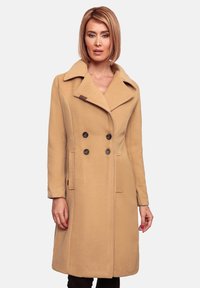 Beige wollen jas met een dubbele rij knopen, grote kraag, twee voorzakken en donkere knopen voor sluiting en accent.