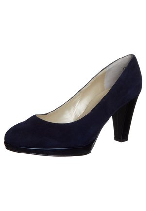 Granatowe zamszowe czółenko z okrągłym noskiem, z połyskującym czarnym akcentem na czubku, oraz trzypalcowym blokowym obcasem. Gładka podszewka wewnętrzna.