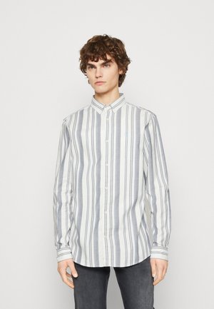 Camisa de botones a rayas en gris claro y azul oscuro, con un cuello clásico y un pequeño logo bordado en el lado izquierdo del pecho.