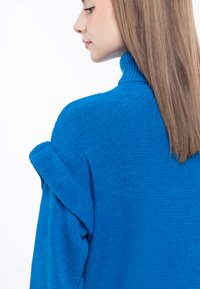 Pulover tricotat albastru cu guler înalt și material texturat. Dispune de un design cu umeri lăsați și spate fără cusături, evidențiind o culoare vibrantă.