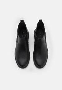 Chaussures noires à enfiler en cuir lisse avec des panneaux élastiques sur les côtés, bout rond, semelle intérieure rembourrée et semelle extérieure résistante en caoutchouc.
