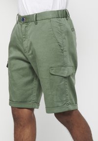 Grüne Cargo-Shorts aus Baumwollmischung, mit Knopfverschluss, seitlichen Taschen und umgeschlagenen Säumen für eine lässige Passform.