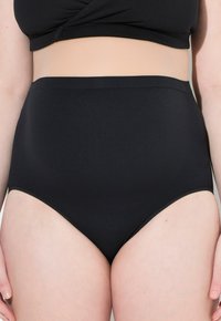 Vysoké černé bikini kalhotky, vyrobené z hladké tkaniny s bezešvou konstrukcí a minimálním švem podél okrajů.