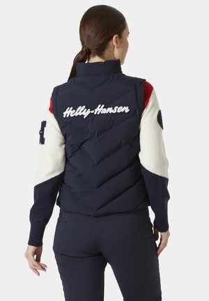 Navy puffer vest with white embroidered "Helly-Hansen" logo on the back, featuring color-block knit sleeves in red, white, and navy.